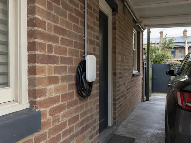 Wall-mounted EV charger on a brick exterior wall beside a driveway in Rozelle