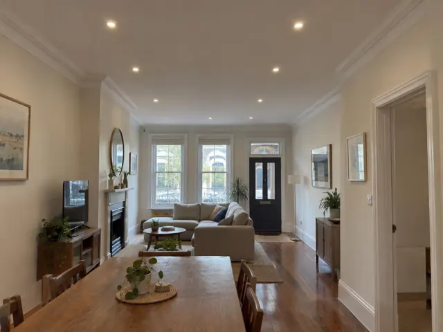 Living room with recessed downlights, fireplace, sofa and timber floor in a traditional terrace interior in Rozelle