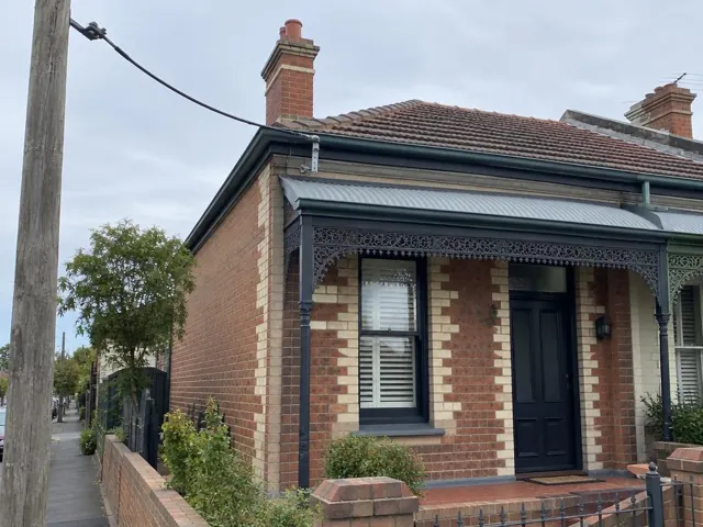 Overhead service cable and attachment bracket on a brick terrace house exterior in Lilyfield